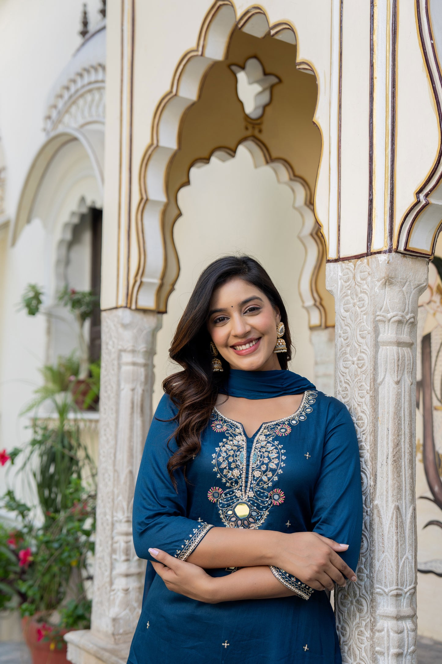 Woman in a blue traditional outfit standing in front of ornate architecture