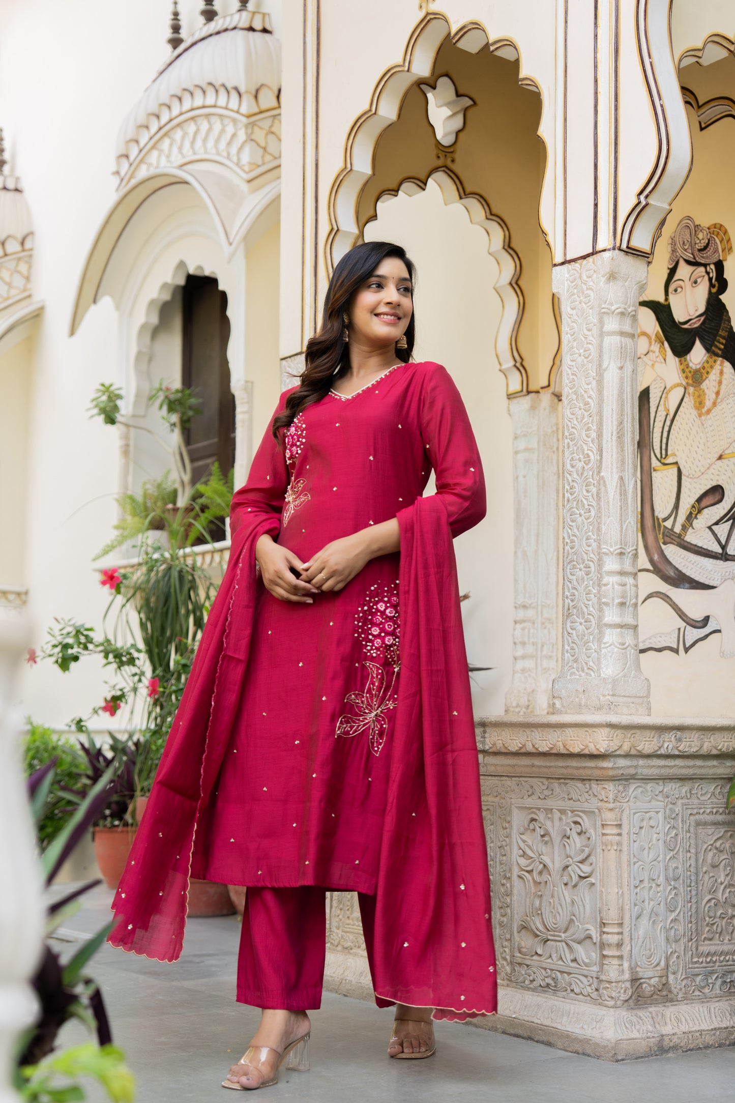 Woman in a pink traditional outfit standing in front of an ornate architectural background