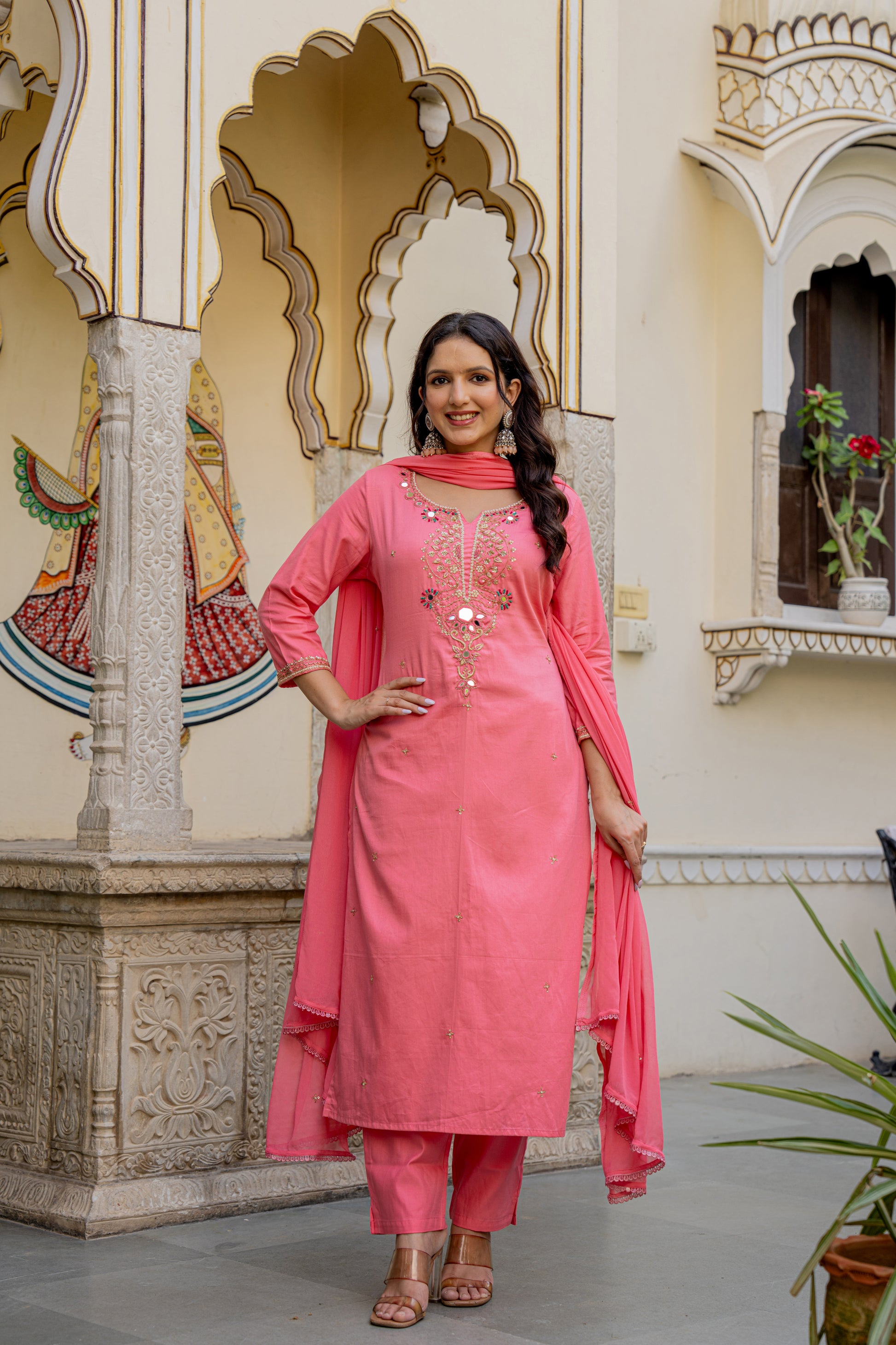 Woman in a pink traditional outfit which is a kurta set designed for wedding standing in an ornate indoor setting