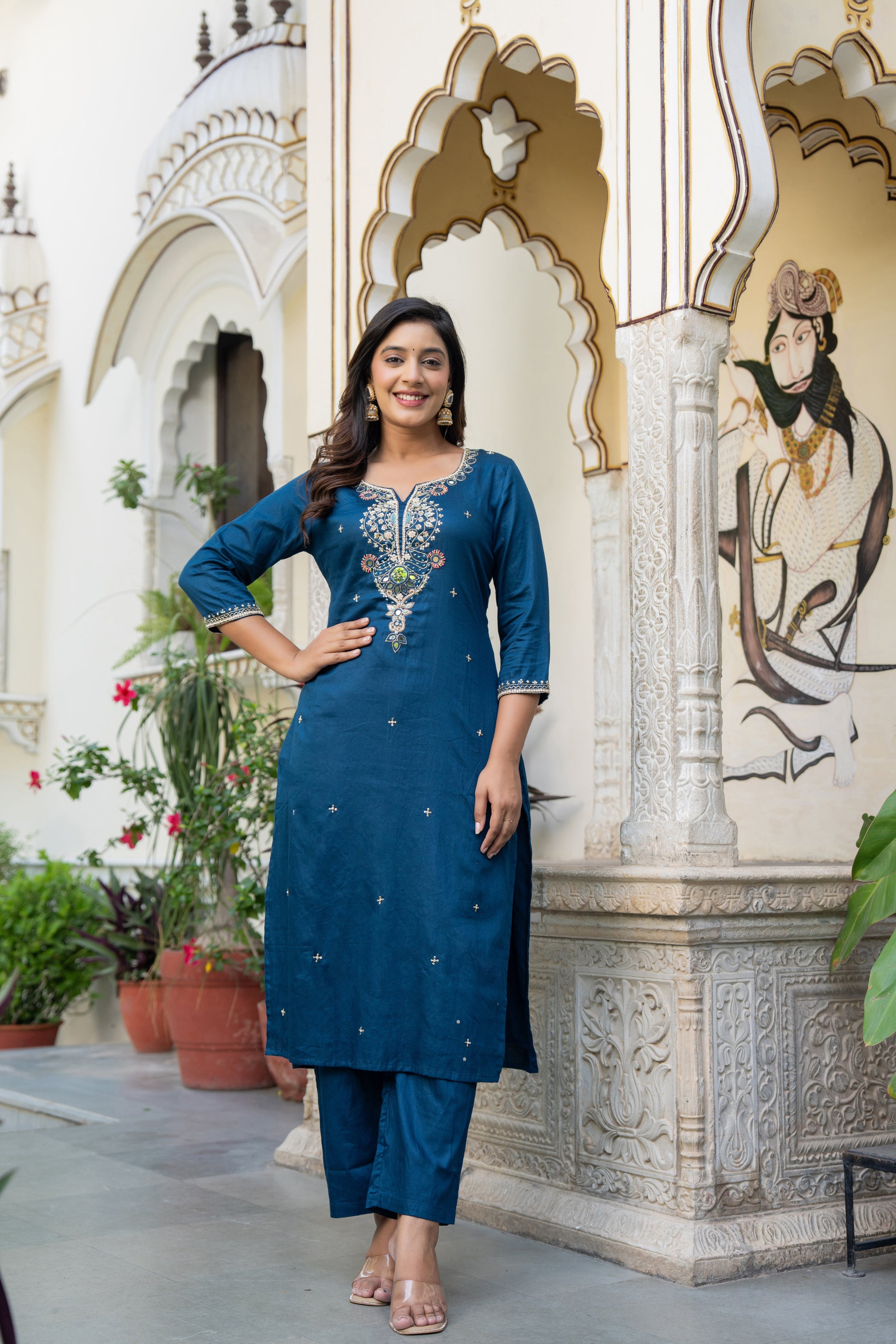 Woman in a blue traditional outfit standing in front of an ornate architectural background