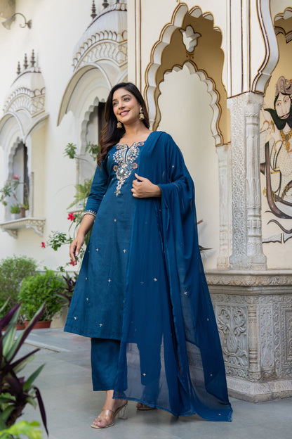 Woman in a teal blue wedding wear kurta set standing in front of an ornate architectural background