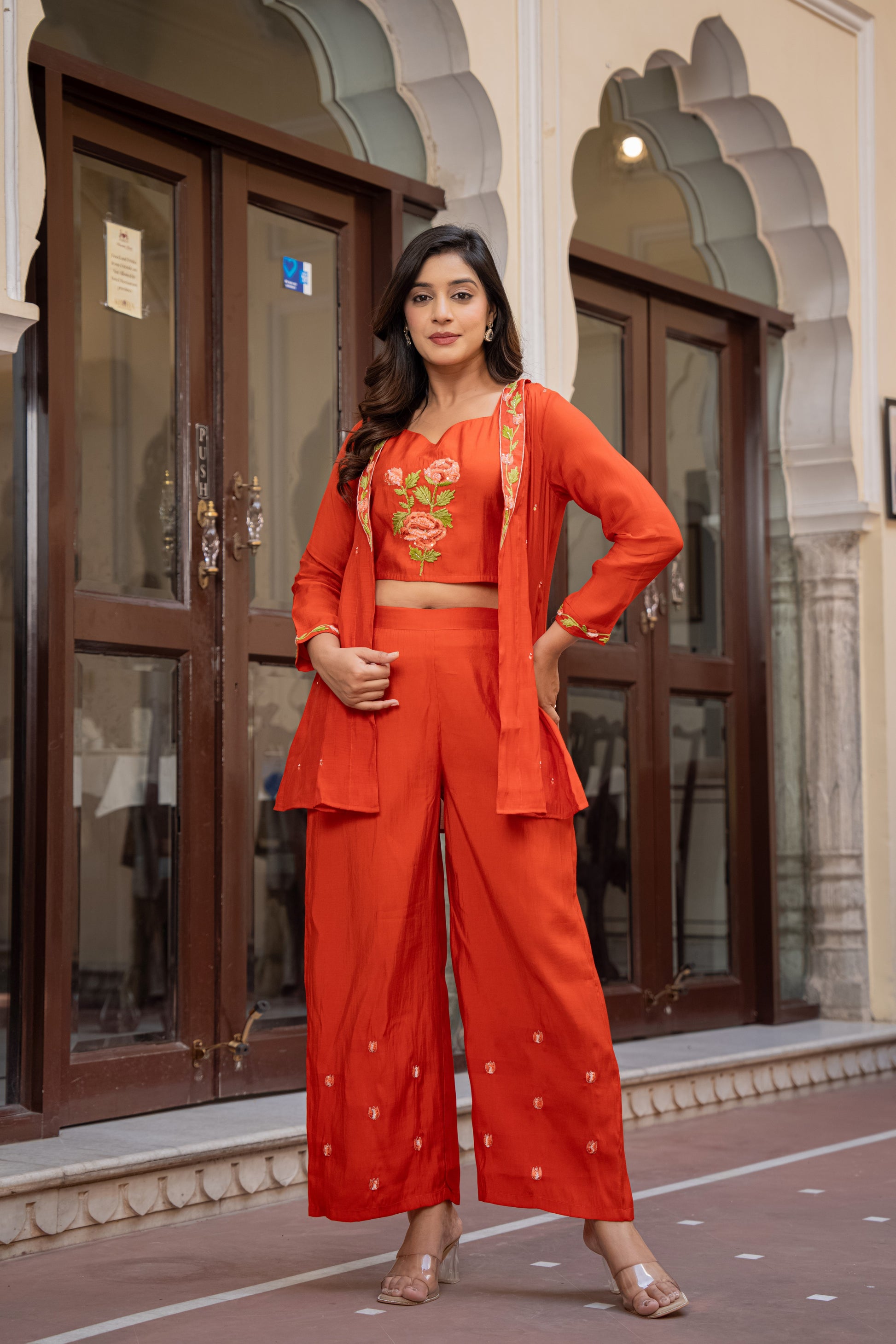 Woman wearing an elegant orange kurta and palazzo set with floral patterns, styled as festive wear for women in an indoor ambiance.