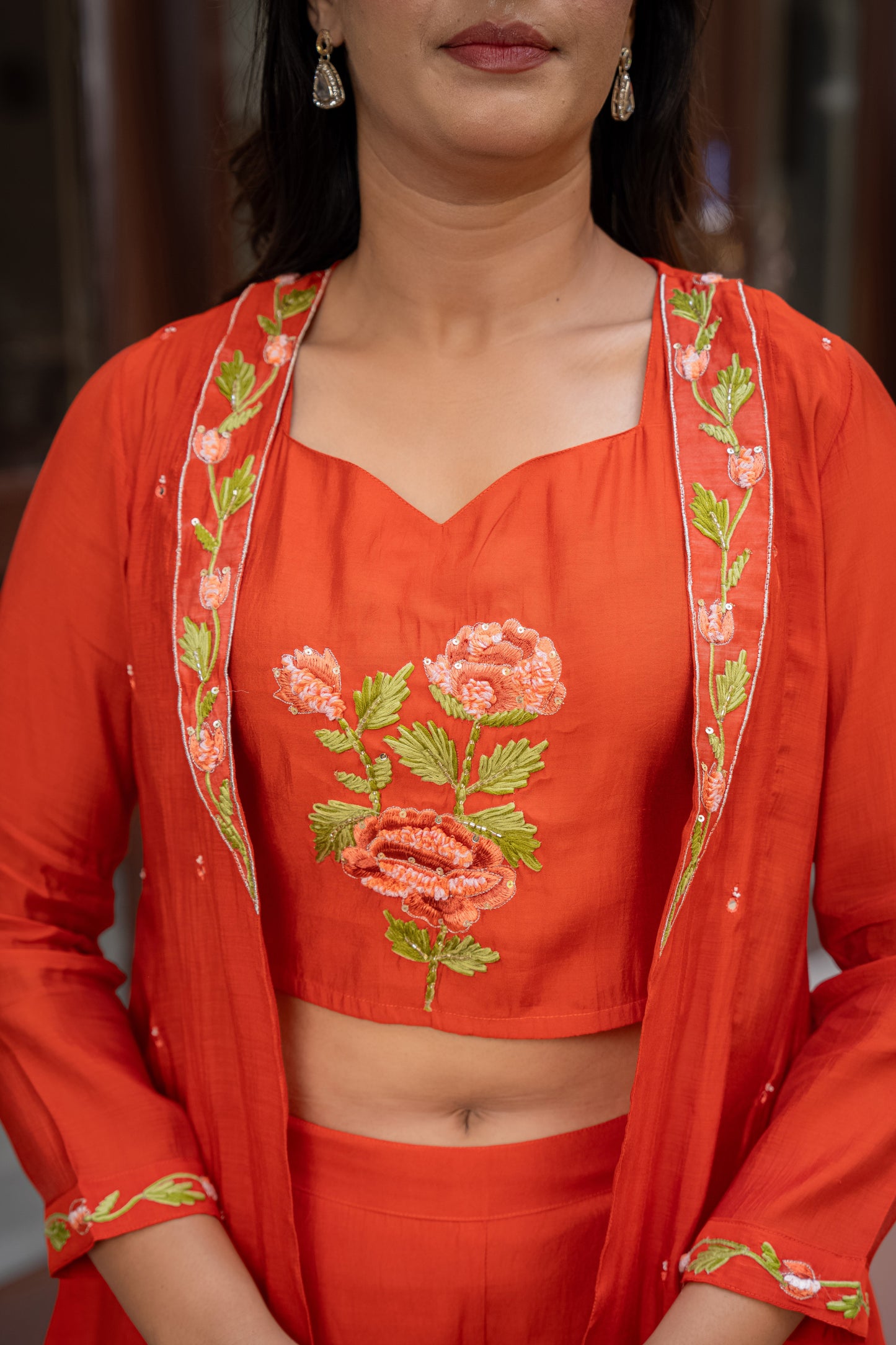 Person wearing an orange embroidered outfit with floral patterns