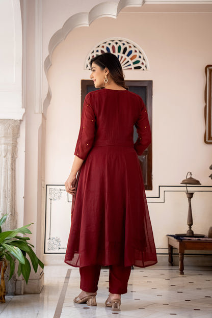 Woman in a red traditional outfit standing in an elegant interior setting.