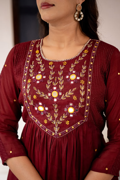 Maroon embroidered dress worn by a woman with a blurred background