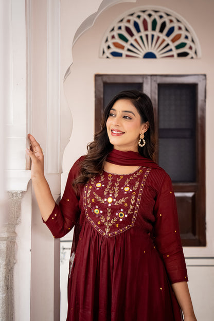 Woman wearing a red embroidered dress standing indoors.