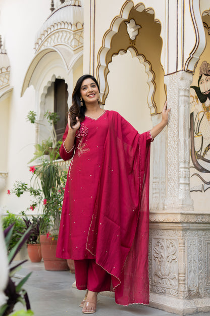 Woman in a pink traditional wedding kurta set standing in front of an ornate architectural background