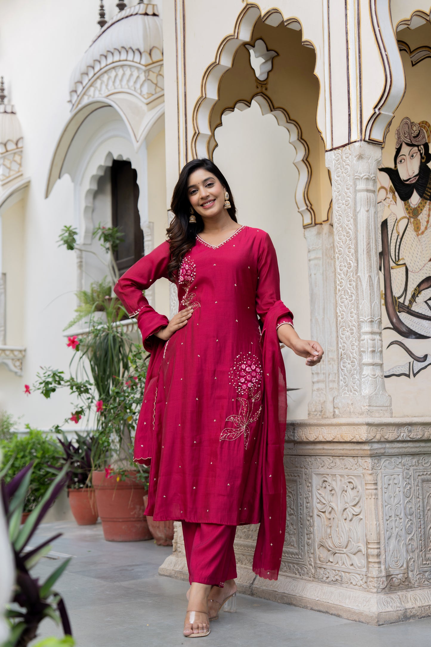 Woman in a pink traditional outfit standing in front of an ornate architectural background