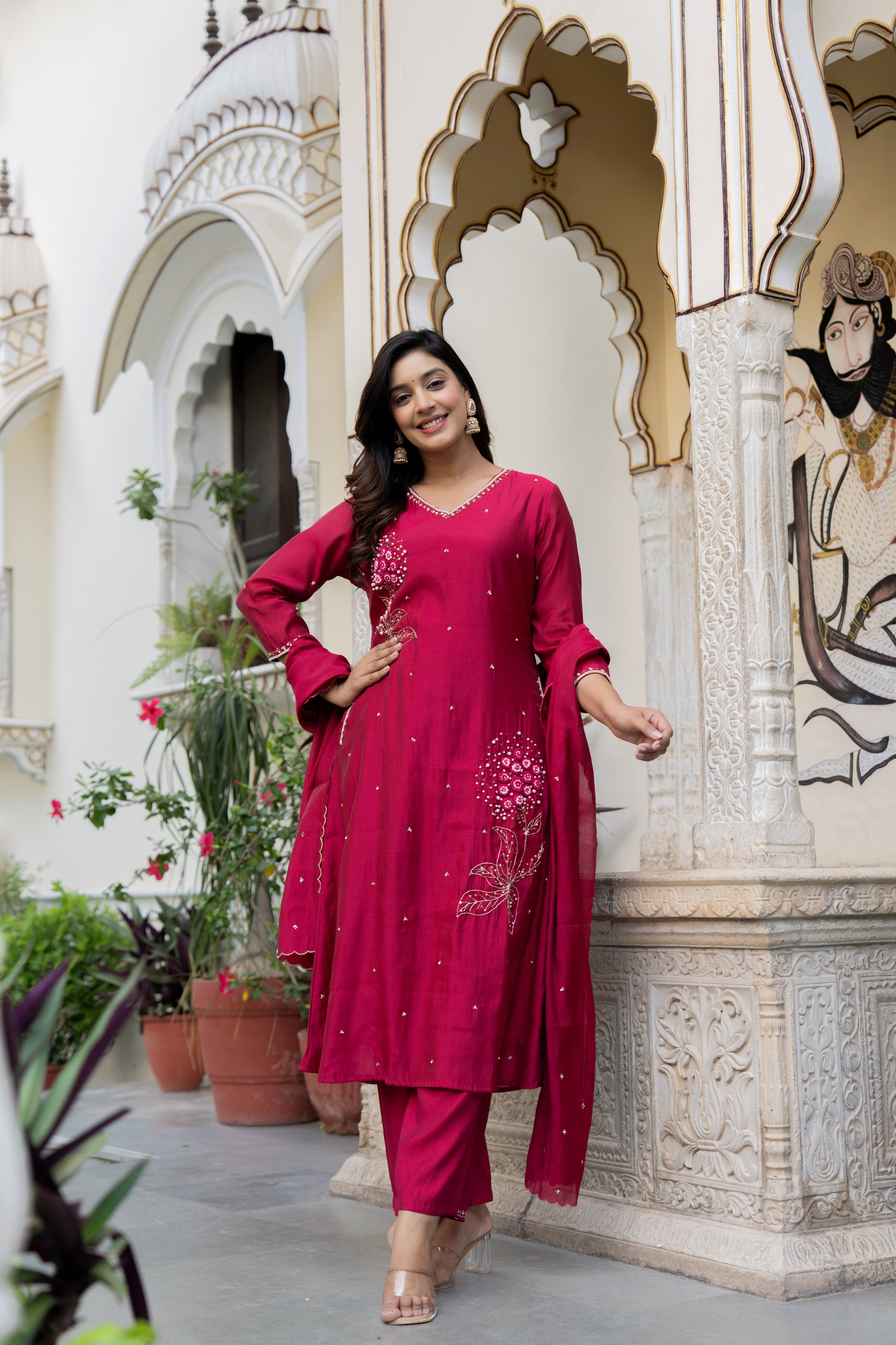 Woman in a pink traditional outfit standing in front of an ornate architectural background