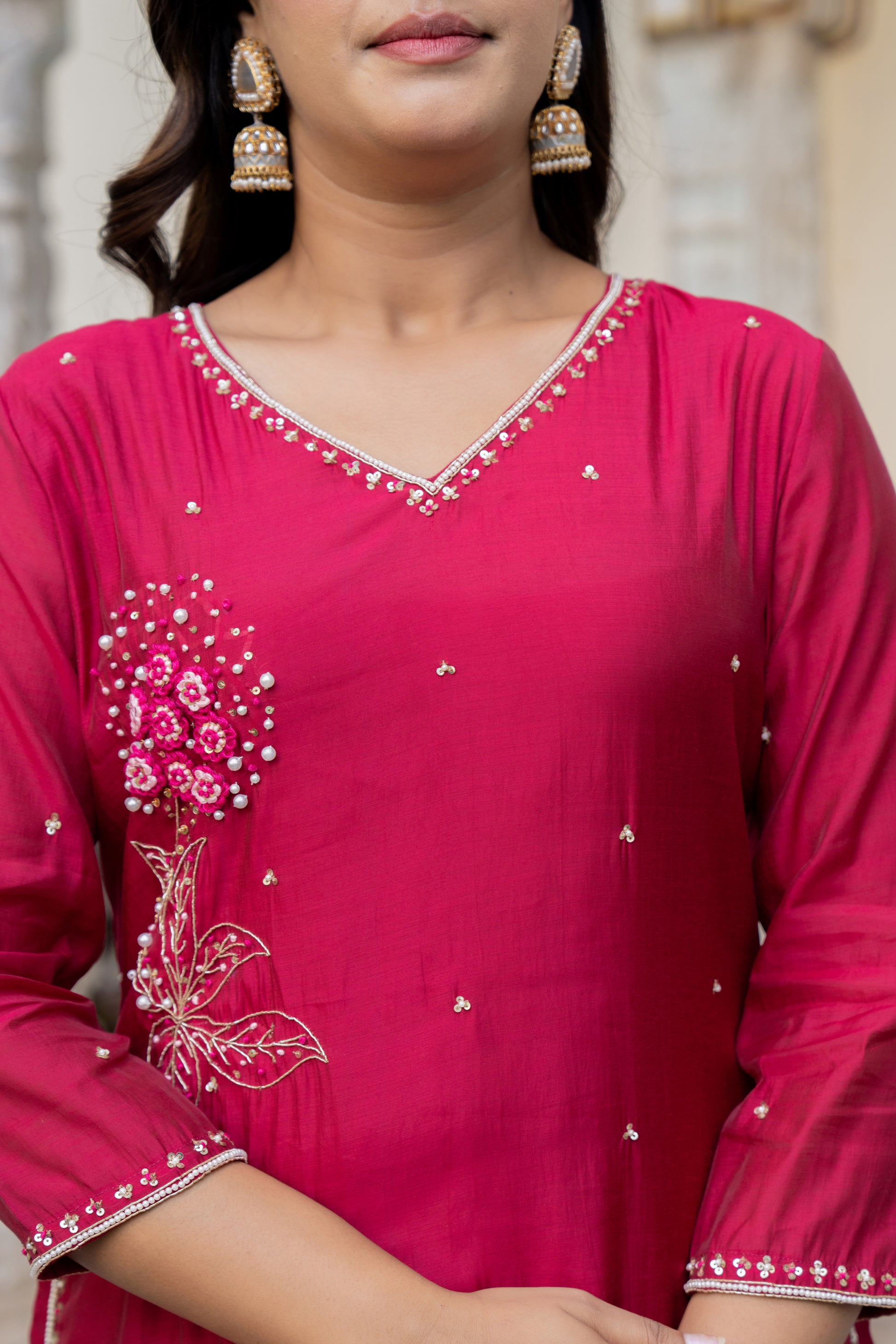 Close-up of a person wearing a pink traditional outfit with intricate white embroidery.