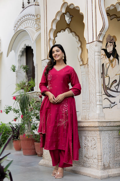 Woman in a Pink kurta set standing in front of an ornate architectural background