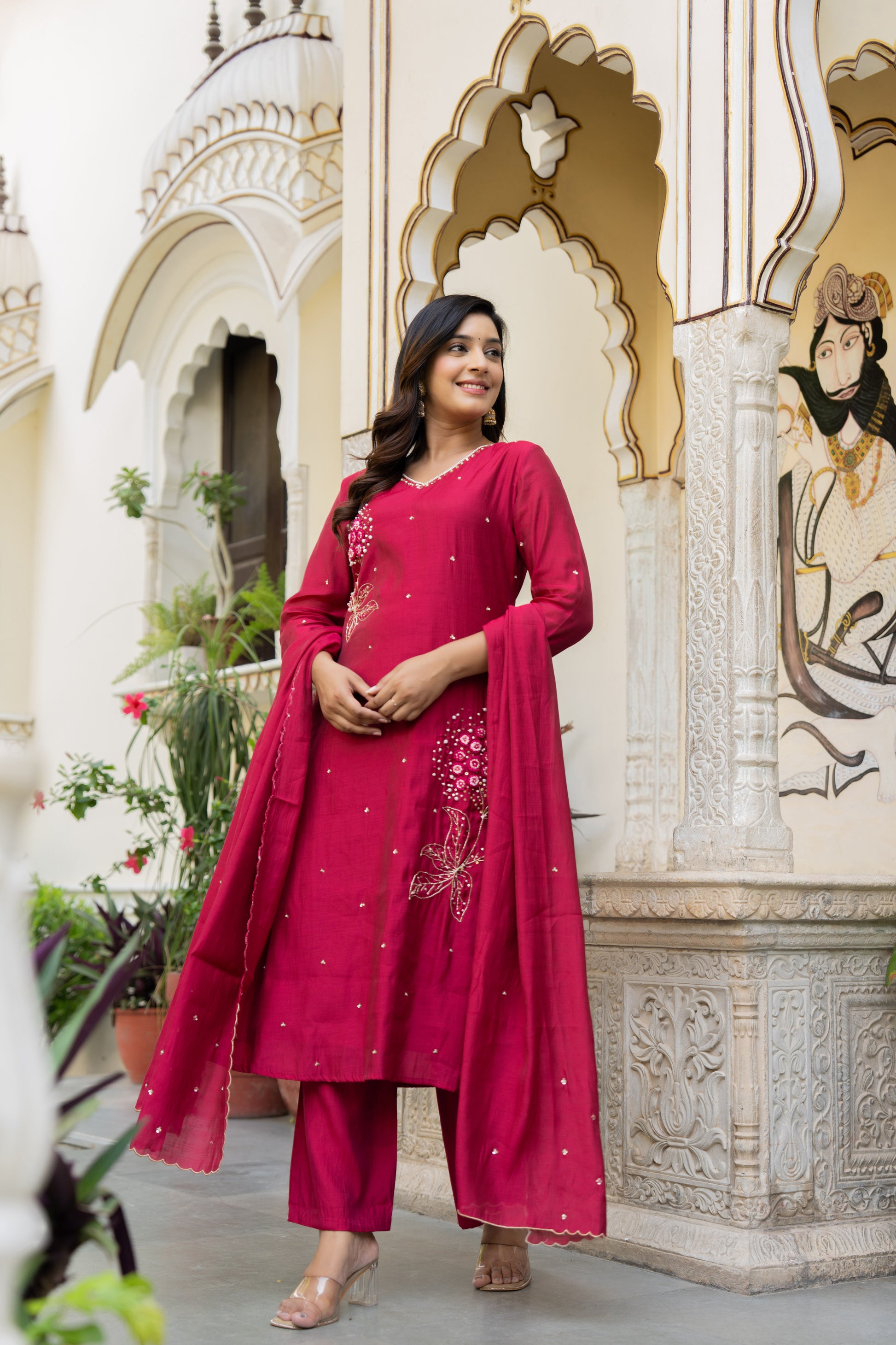 Woman in a pink traditional outfit standing in front of an ornate architectural background