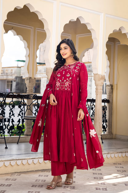 Woman in a red traditional outfit  which is a wedding kurta set for women standing in an ornate architectural setting.