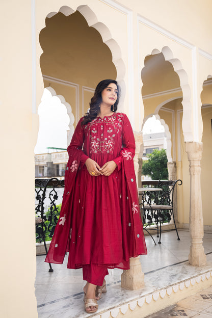Woman in a red traditional outfit standing in an ornate architectural setting.