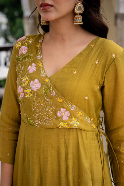 Woman wearing a mustard yellow dress with floral embroidery, indoors.