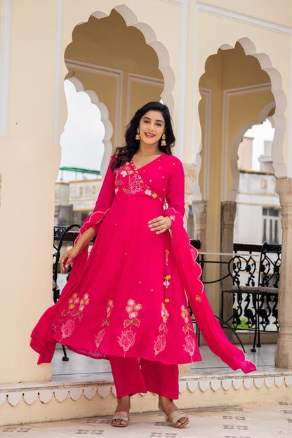 Woman in a bright pink anarkali kurta set with dupatta standing in front of ornate arches, showcasing festive kurta sets for women