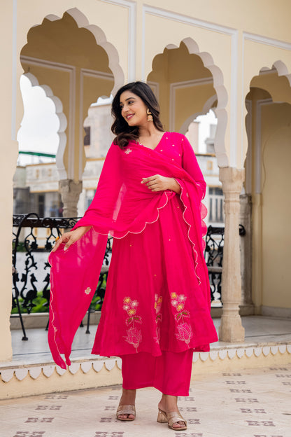 Woman in a bright pink traditional outfit standing in front of ornate arches, reflecting elegant ethnic sets for women