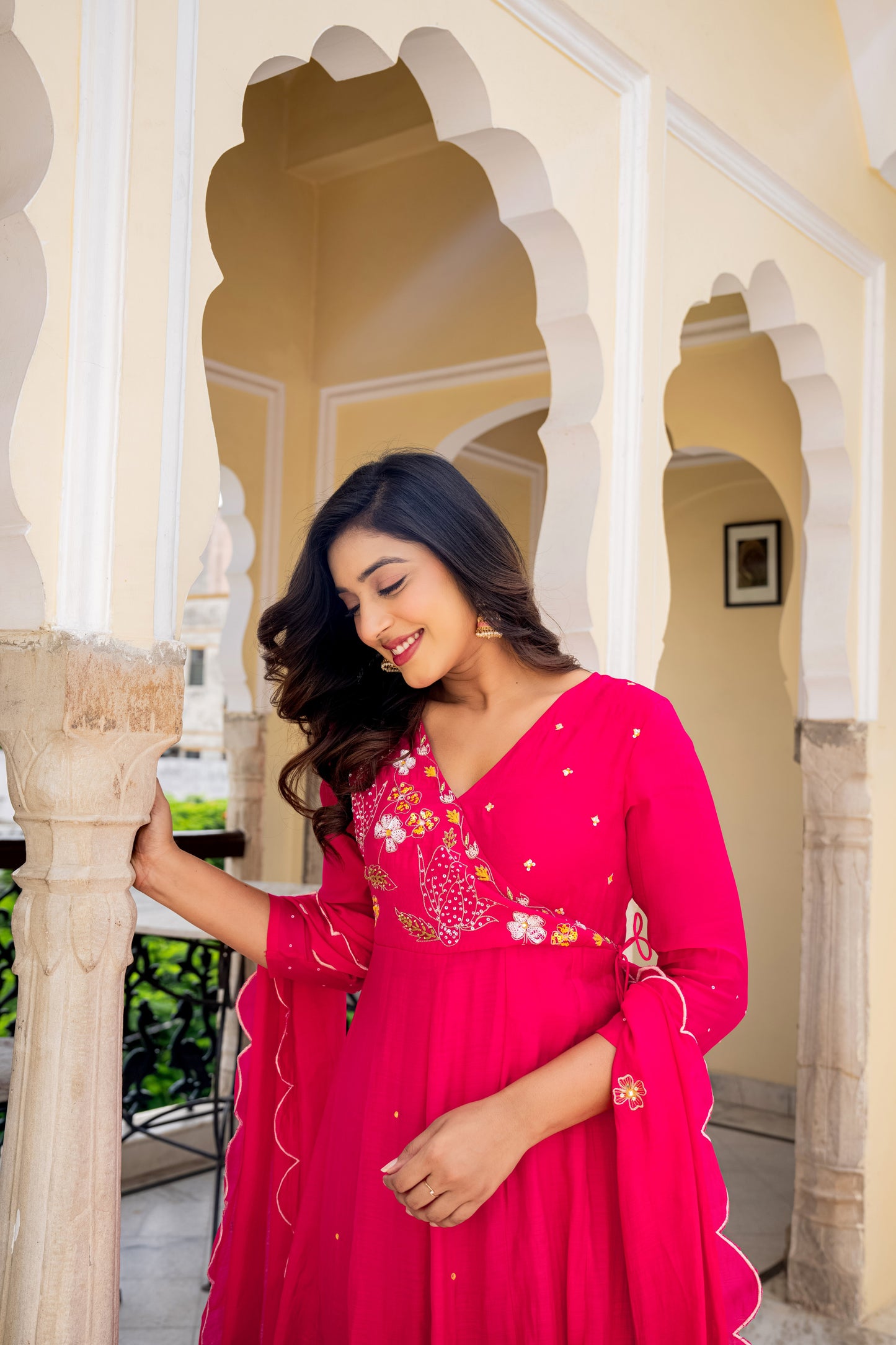 Lady in a pink kurta pant set for women standing in front of ornate arches, blending traditional and modern style