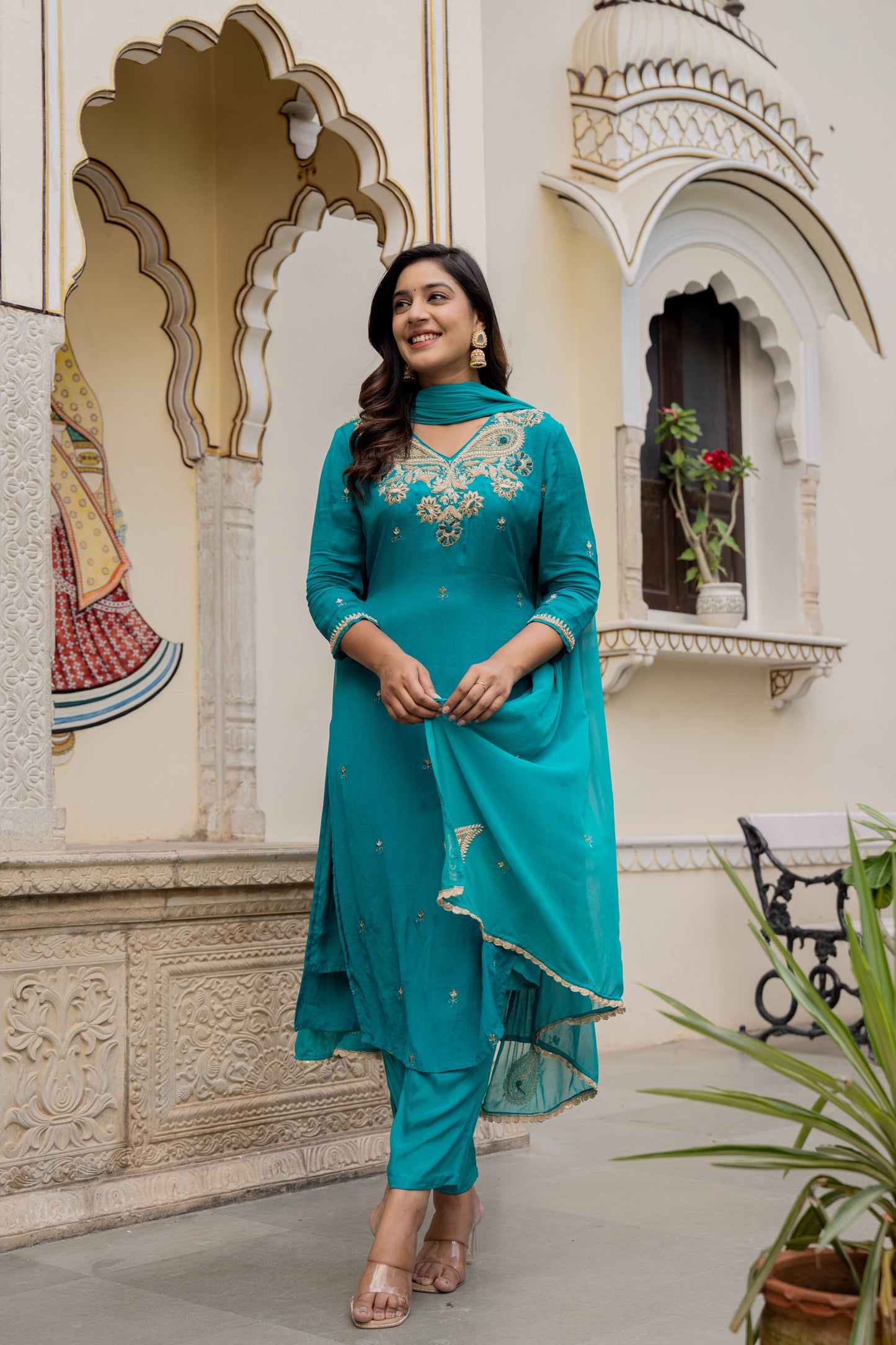 Woman in a teal green designer kurta set standing in front of an ornate building, styled as a kurta set for wedding
