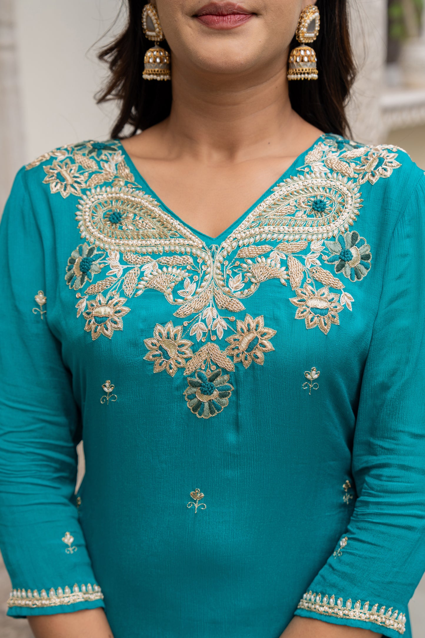 Teal embroidered dress with gold details worn by a woman