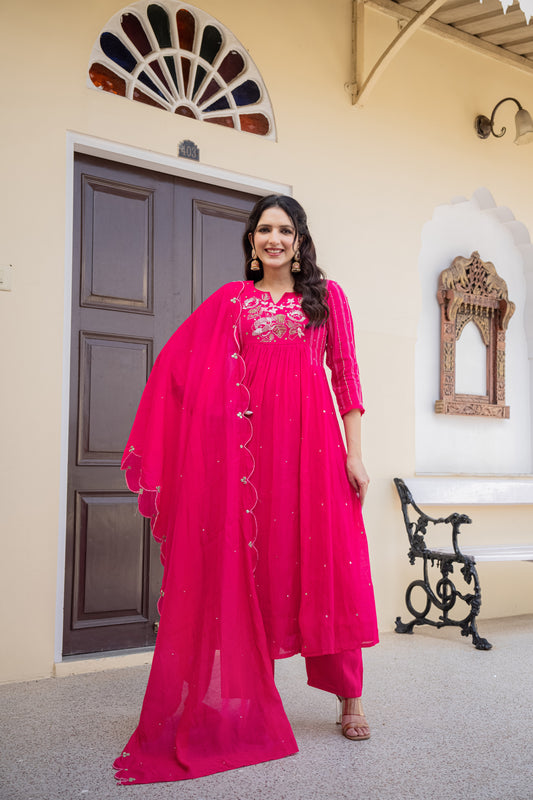 Elegant woman dressed in a pink anarkali kurta set posing in a beautifully adorned room, perfect festive wear for women