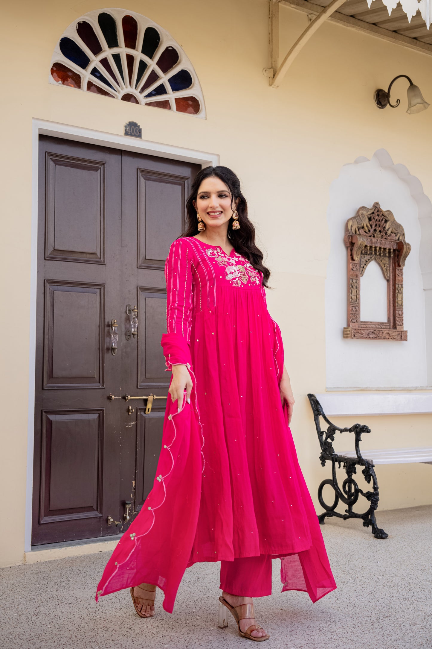 pink anarkali kurta set with dupatta worn by a woman indoors surrounded by decorative details, ideal ethnic set for women