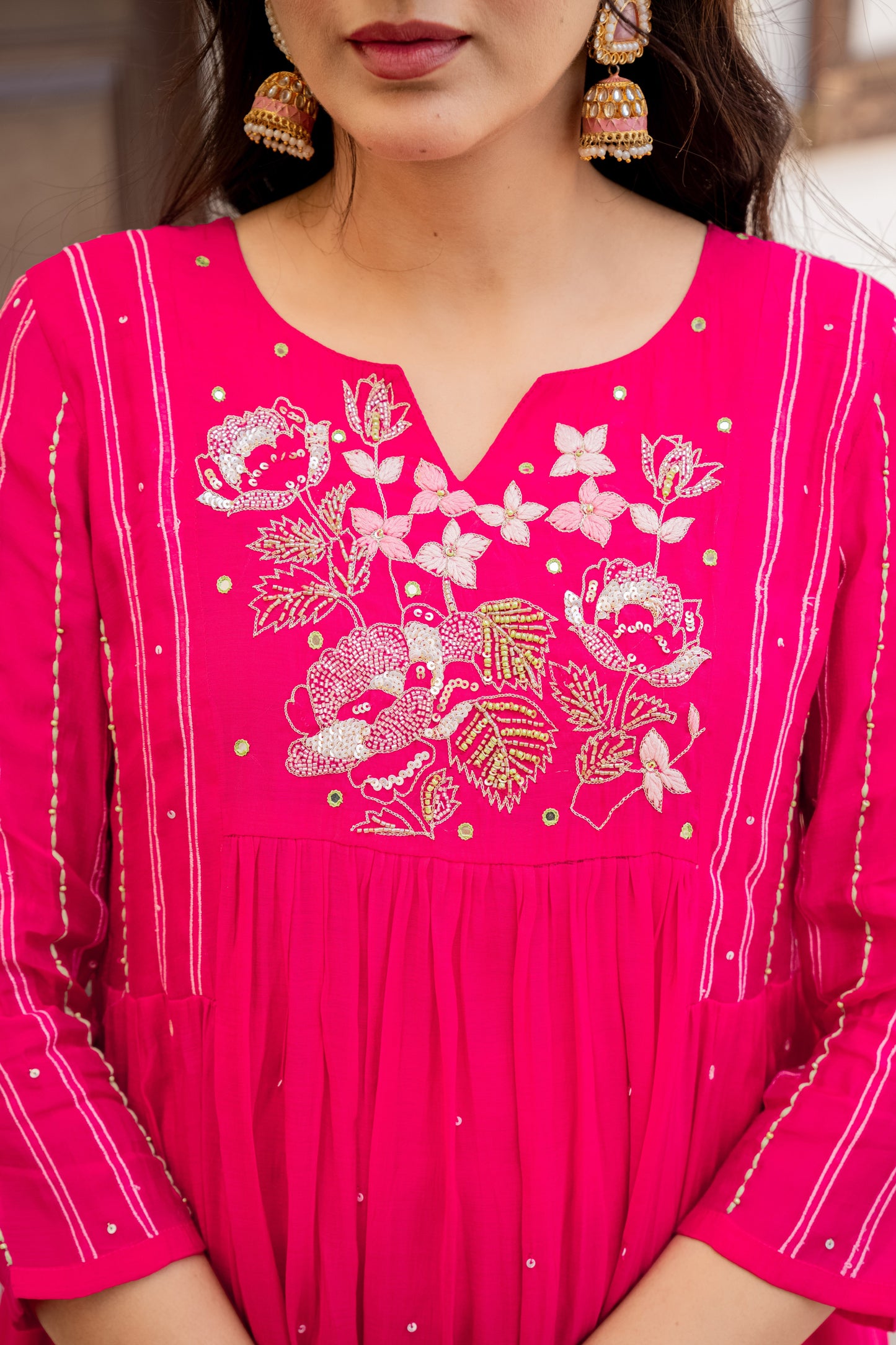 Woman wearing a bright pink dress with floral embroidery