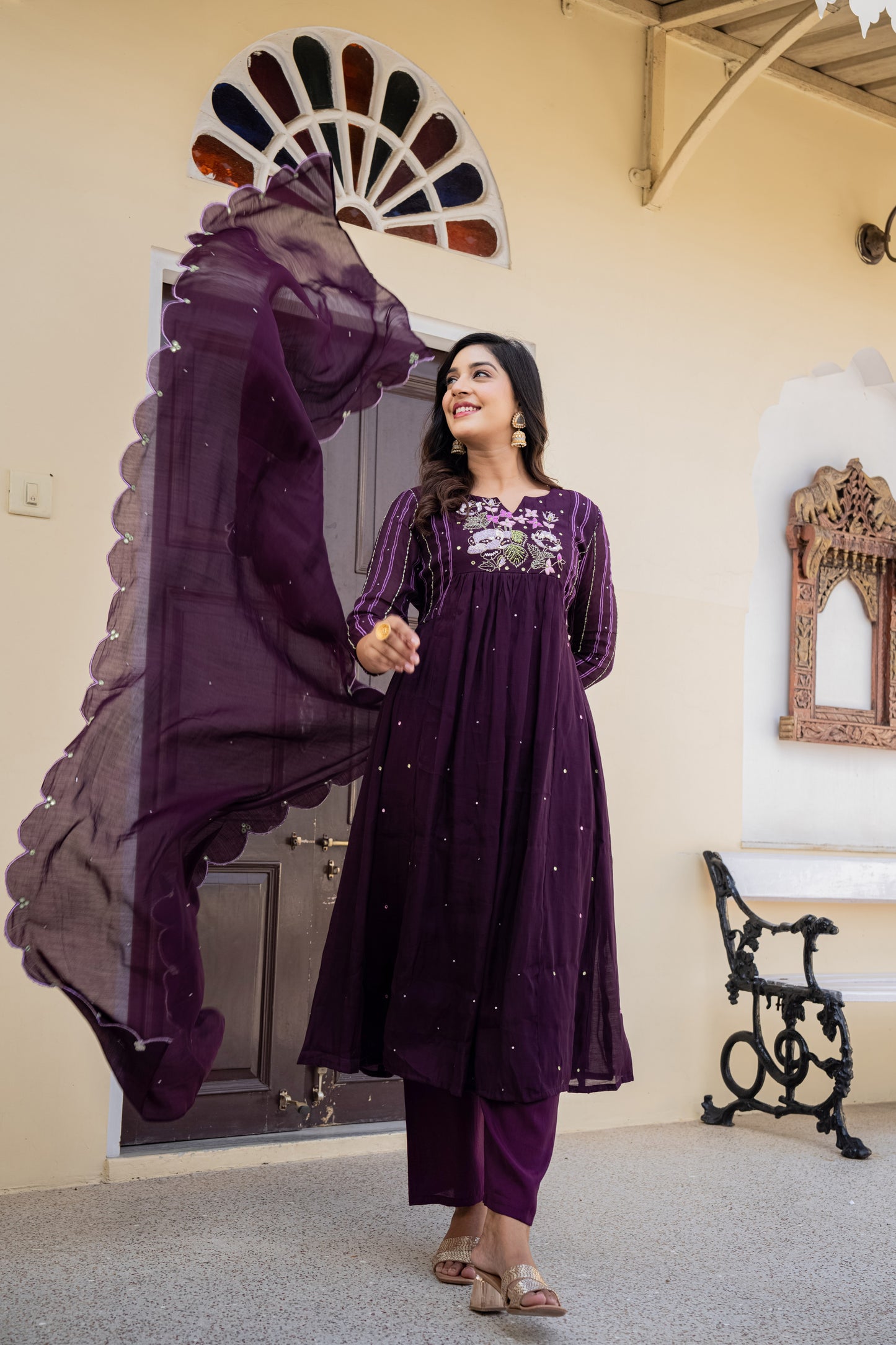 Woman in a purple anarkali kurta set standing indoors, styled as festive kurta sets for women with decorative elements.