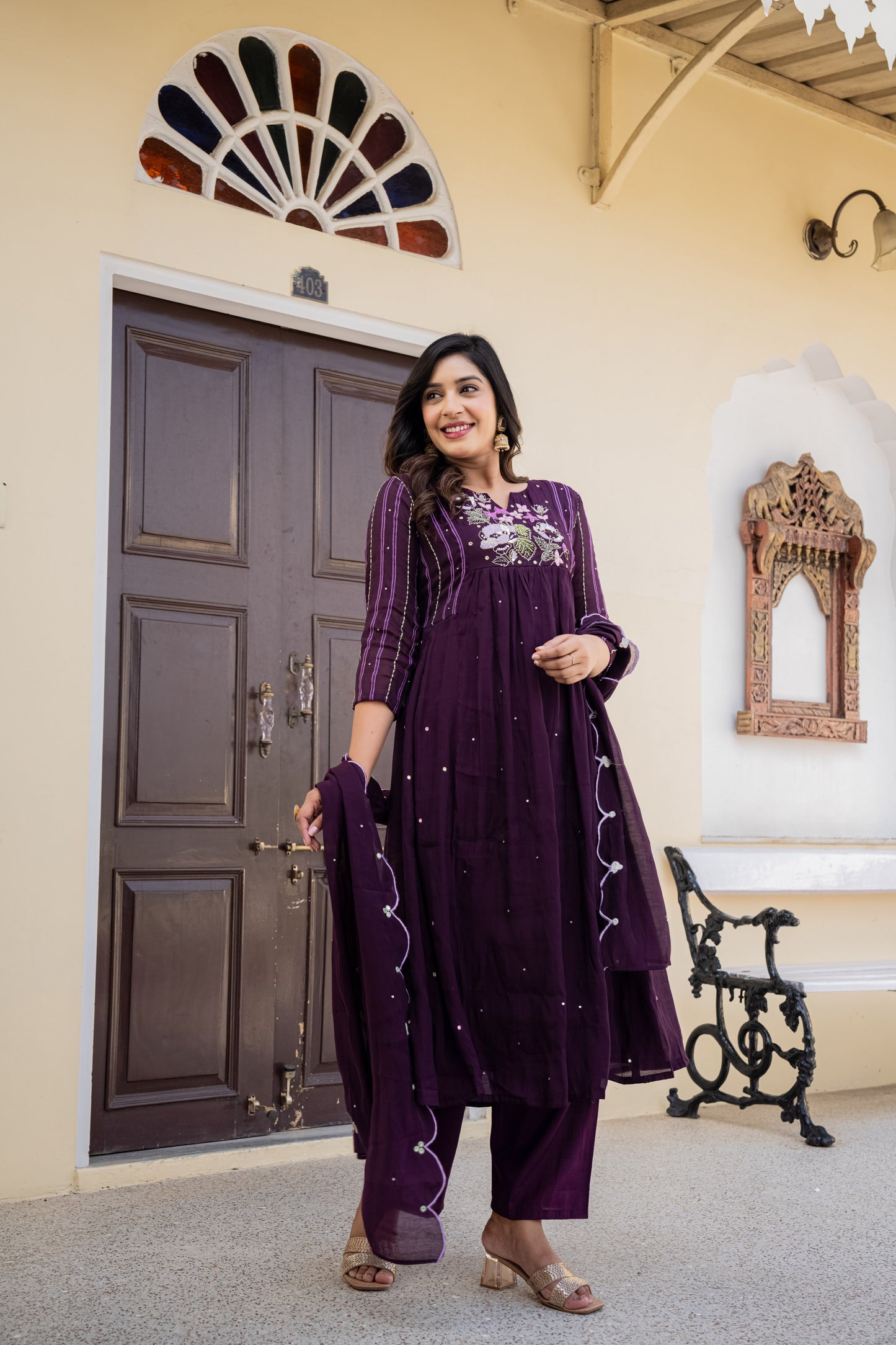 Purple traditional anarkali kurta set worn by a woman indoors with decorative elements, styled as festive wear for women