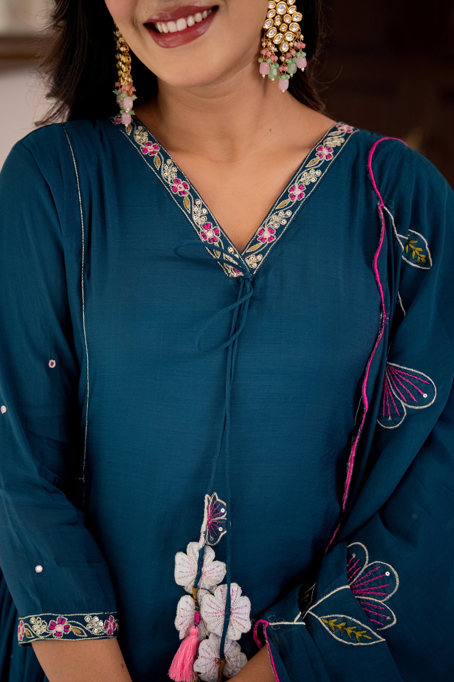 Woman wearing a blue embroidered traditional outfit with floral patterns.