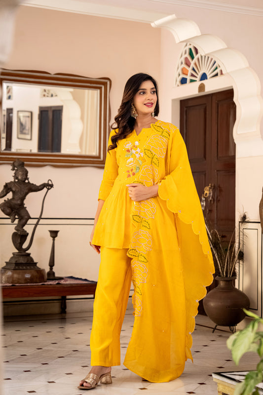 Woman wearing a bright yellow kurta and palazzo set with traditional patterns, styled as festive wear for women indoors.