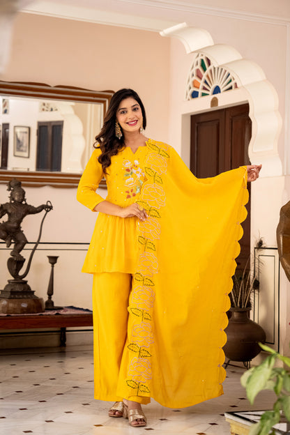 Elegant woman in a yellow kurta pant set, standing indoors with decorative elements, showcasing modern ethnic sets for women