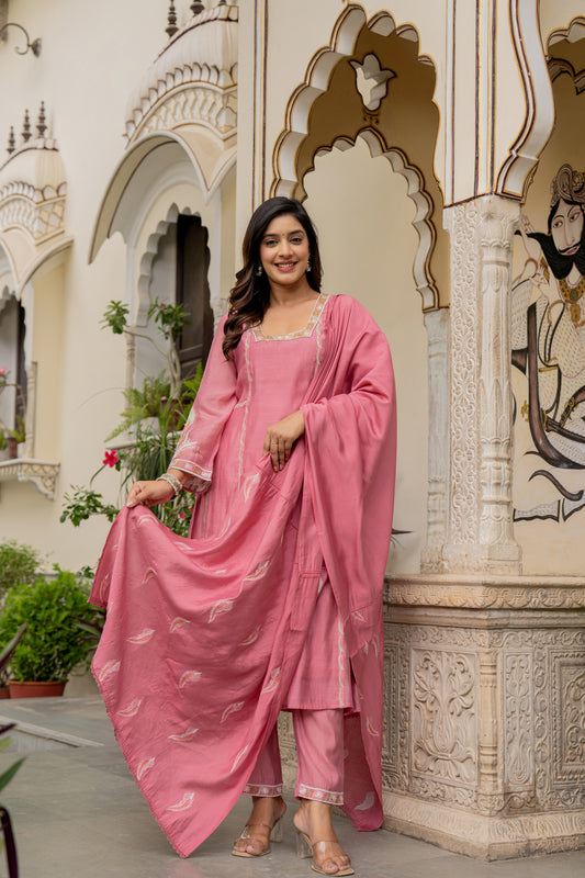 Woman in a pink traditional outfit which is a kurta set  for wedding standing in front of an ornate architectural background