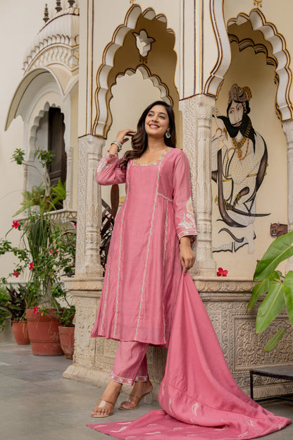 Woman in a pink traditional outfit which is wedding wear kurta set standing in front of an ornate architectural background.