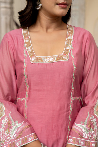Close-up of a pink traditional outfit with intricate white embroidery on a blurred background