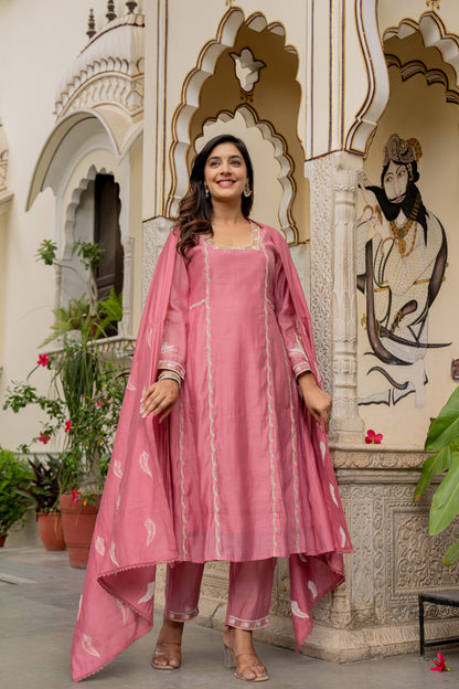 Stylish lady dressed in a pink kurta pant set, posed in front of decorative architectural details representing a wedding kurta set for women.