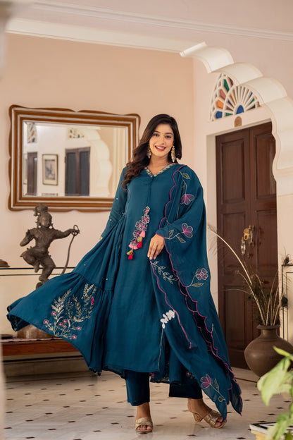Woman in a teal embroidered Kurta set for wedding outfit standing in a decorated room.